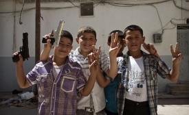 A group of young Syrian boys with toy guns mug for the camera.