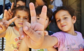 Syrian refugee children at a half-built apartment block near Reyfoun in Lebanon, close to the border with Syria, give the peace sign. The families fled Syria due to the war and are now living on a building site. (Photo: Eoghan Rice)