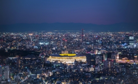 Overhead aerial view of the new National Stadium with Tokyo's skyline in twilight time, fully completed main stadium for Tokyo Olympic Summer Games 2020. Image via iStock.