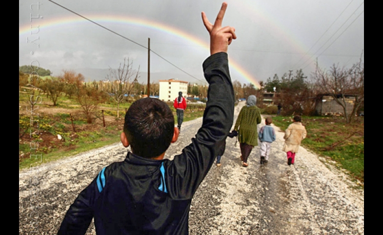 Hassan Saad, 13, who fled Idlib in Syria, flashes a victory sign while walking outside the refugees camp near the Turkish-Syrian border in the southeastern city of Yayladagi