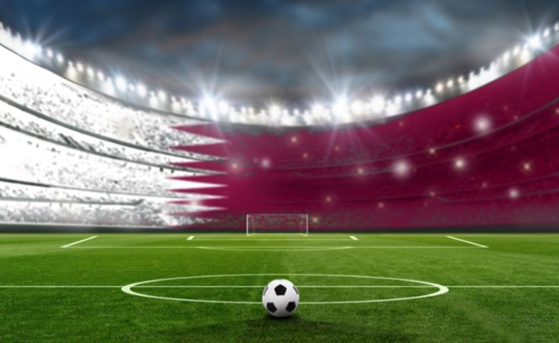 A football in a stadium with colors of the national flag of Qatar by FotografieLink via Canva