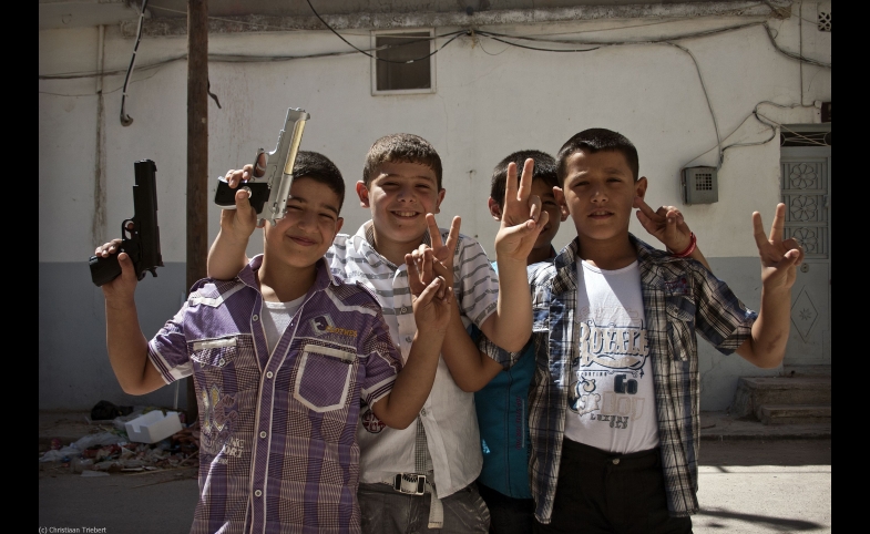 A group of young Syrian boys with toy guns mug for the camera.