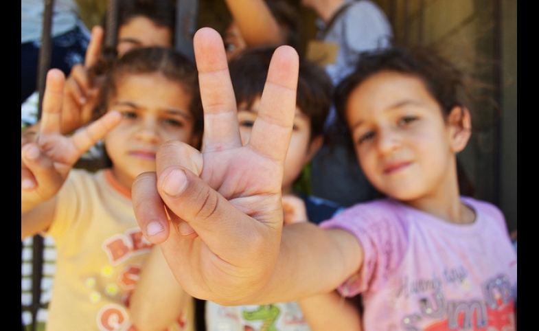 Syrian refugee children at a half-built apartment block near Reyfoun in Lebanon, close to the border with Syria, give the peace sign. The families fled Syria due to the war and are now living on a building site. (Photo: Eoghan Rice)