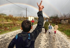 Hassan Saad, 13, who fled Idlib in Syria, flashes a victory sign while walking outside the refugees camp near the Turkish-Syrian border in the southeastern city of Yayladagi