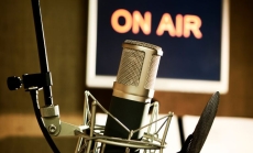 A broadcast microphone complete with pop guard in an audio sound booth by ContentWorks via Canva.com