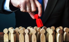 A man pulls the red wooden peg doll out of the crowd by Dorin Tamas via Canva