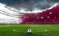 A football in a stadium with colors of the national flag of Qatar by FotografieLink via Canva