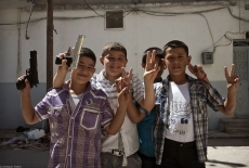 A group of young Syrian boys with toy guns mug for the camera.