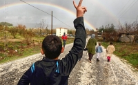 Hassan Saad, 13, who fled Idlib in Syria, flashes a victory sign while walking outside the refugees camp near the Turkish-Syrian border in the southeastern city of Yayladagi