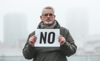 An image of a man holding a sign that says NO by Andrii Zastrozhnov via canva.com