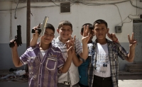 A group of young Syrian boys with toy guns mug for the camera.